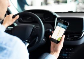 Driver Using Smartphone With Car Navigation App Driving In City