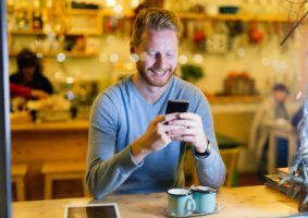 Handsome man using mobile phone in coffee shop