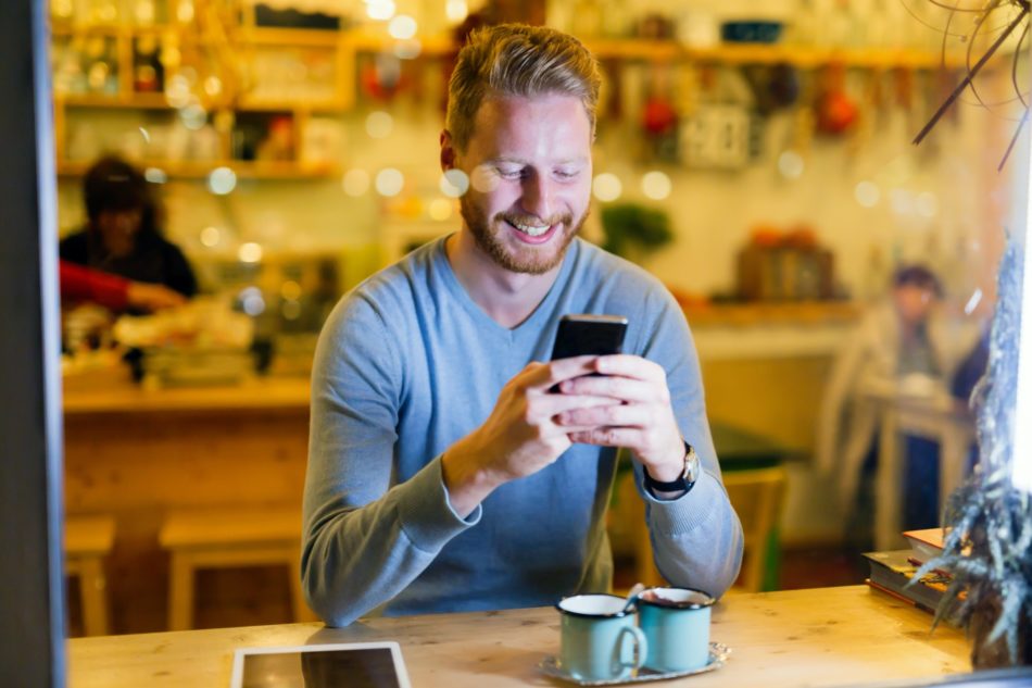 Handsome man using mobile phone in coffee shop