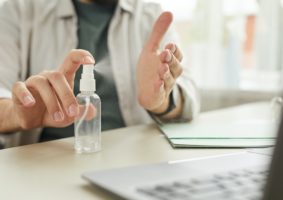 Man Using Hand Sanitizer at Workplace Close Up