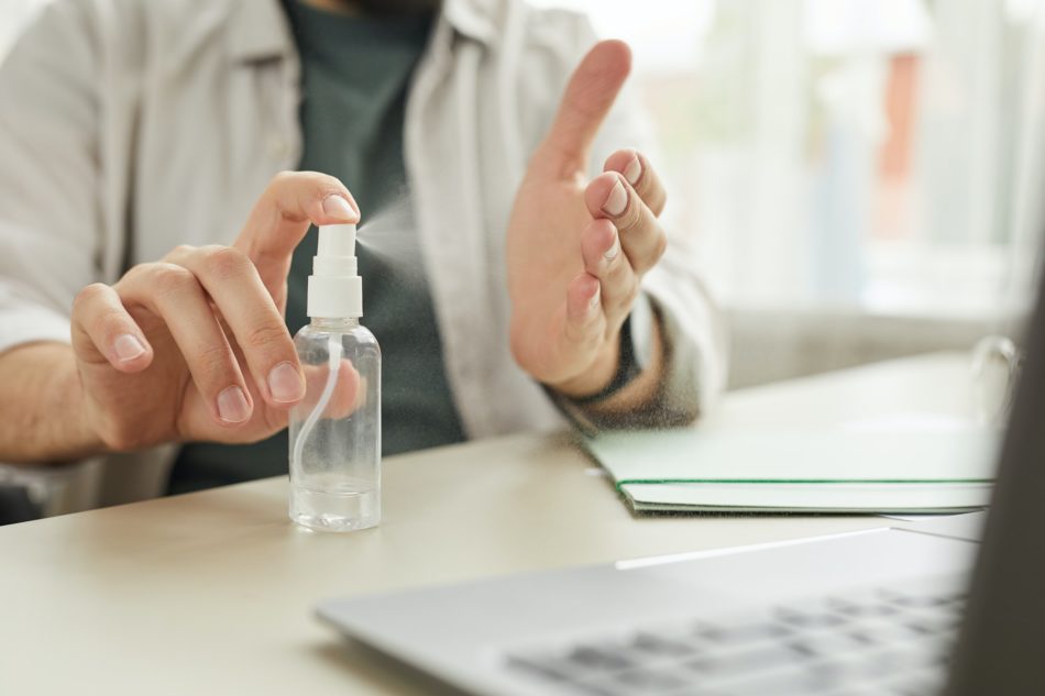 Man Using Hand Sanitizer at Workplace Close Up